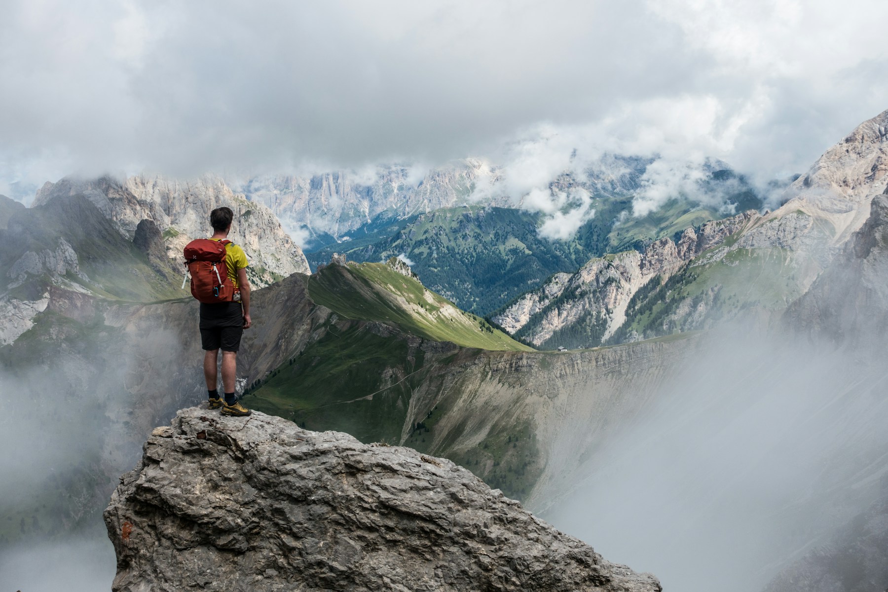 A walker looking across layered mountain peaks in the Dolomites