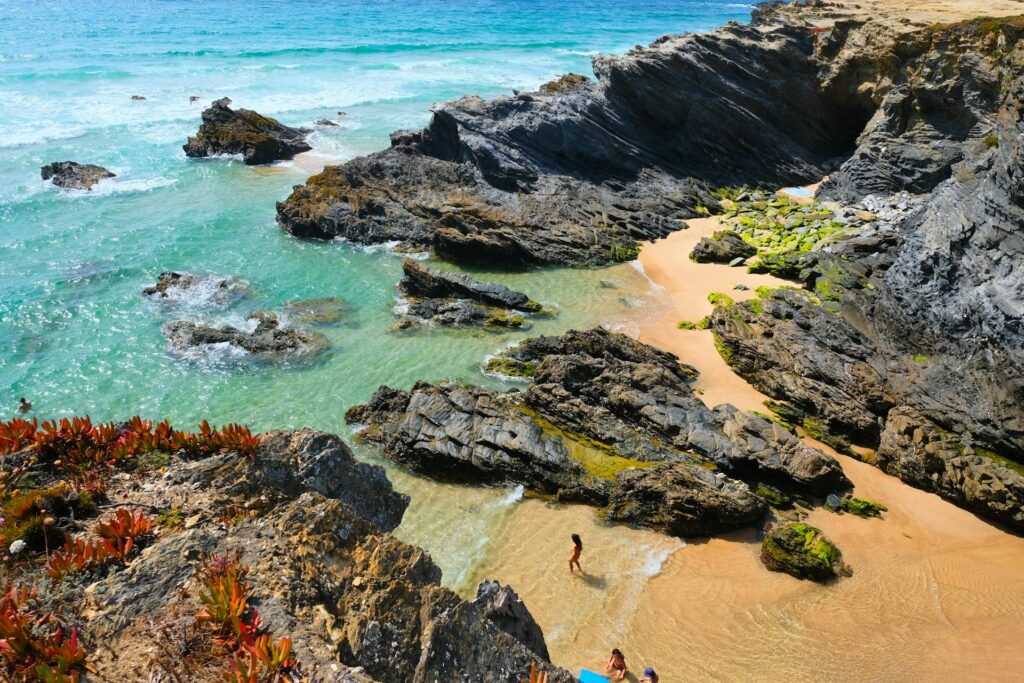 Rocky coastal cliffs surrounding a sandy beach near Porto Covo, Portugal