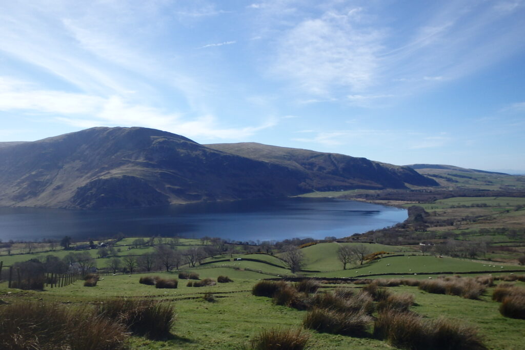 Ennerdale Water and surrounding Lake District hills viewed across green fields