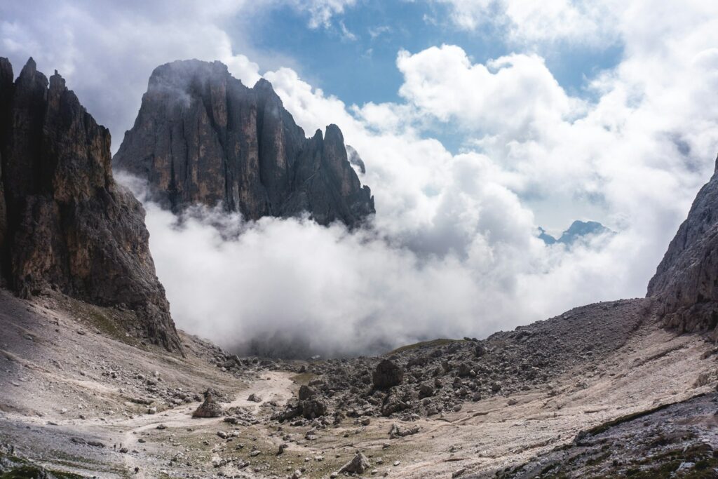 Limestone peaks and a rocky mountain basin beneath broken cloud in the Dolomites