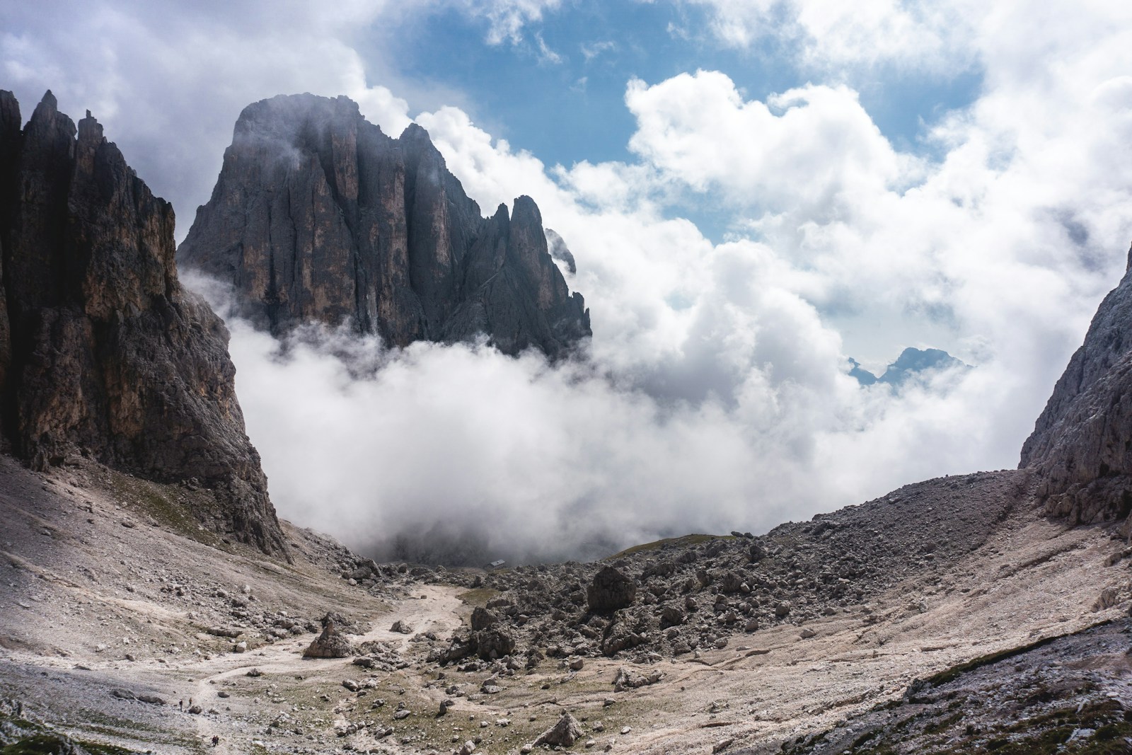 Limestone peaks and a rocky basin beneath broken cloud in the Dolomites